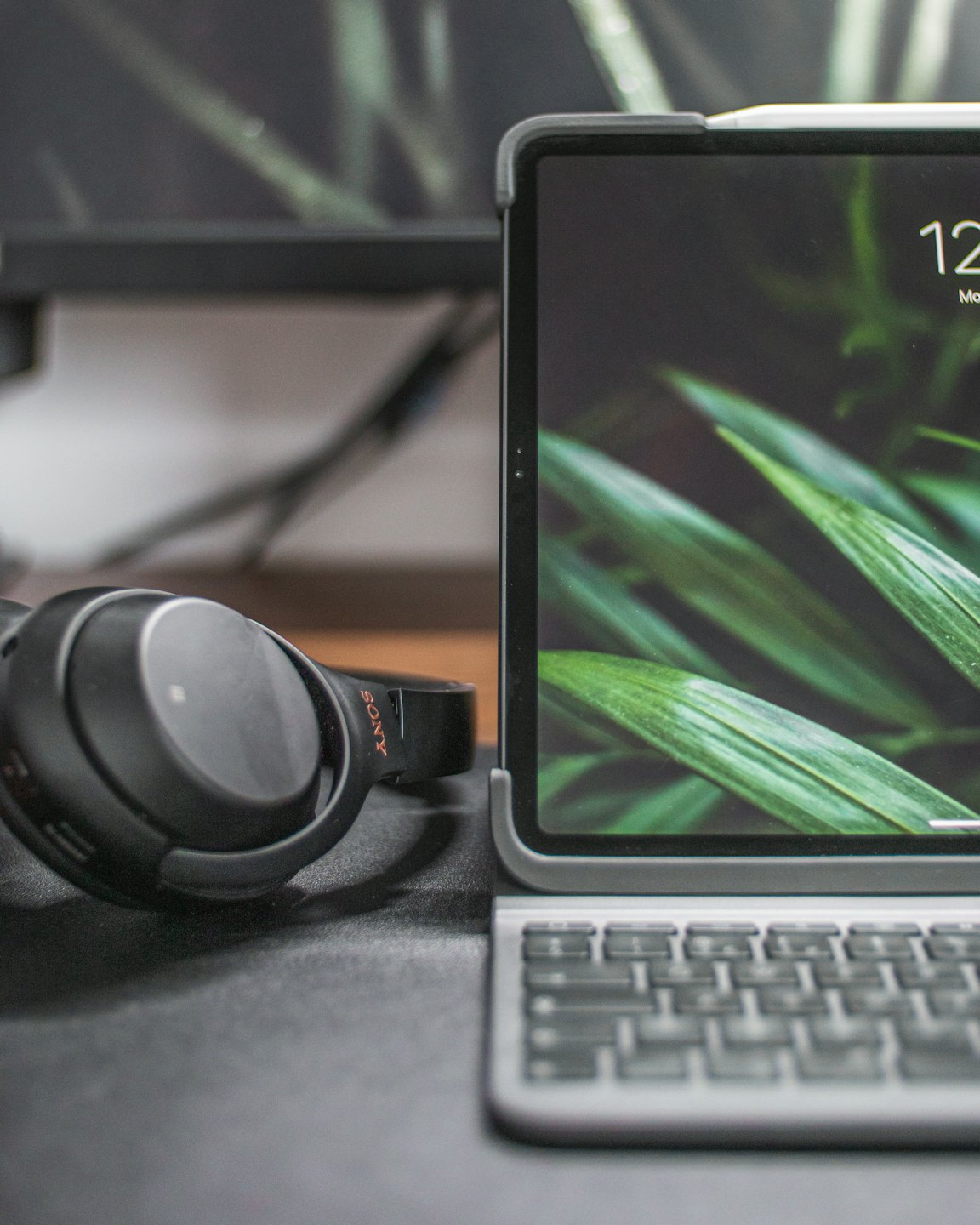 Black headphones rest on a desk beside a tablet computer.